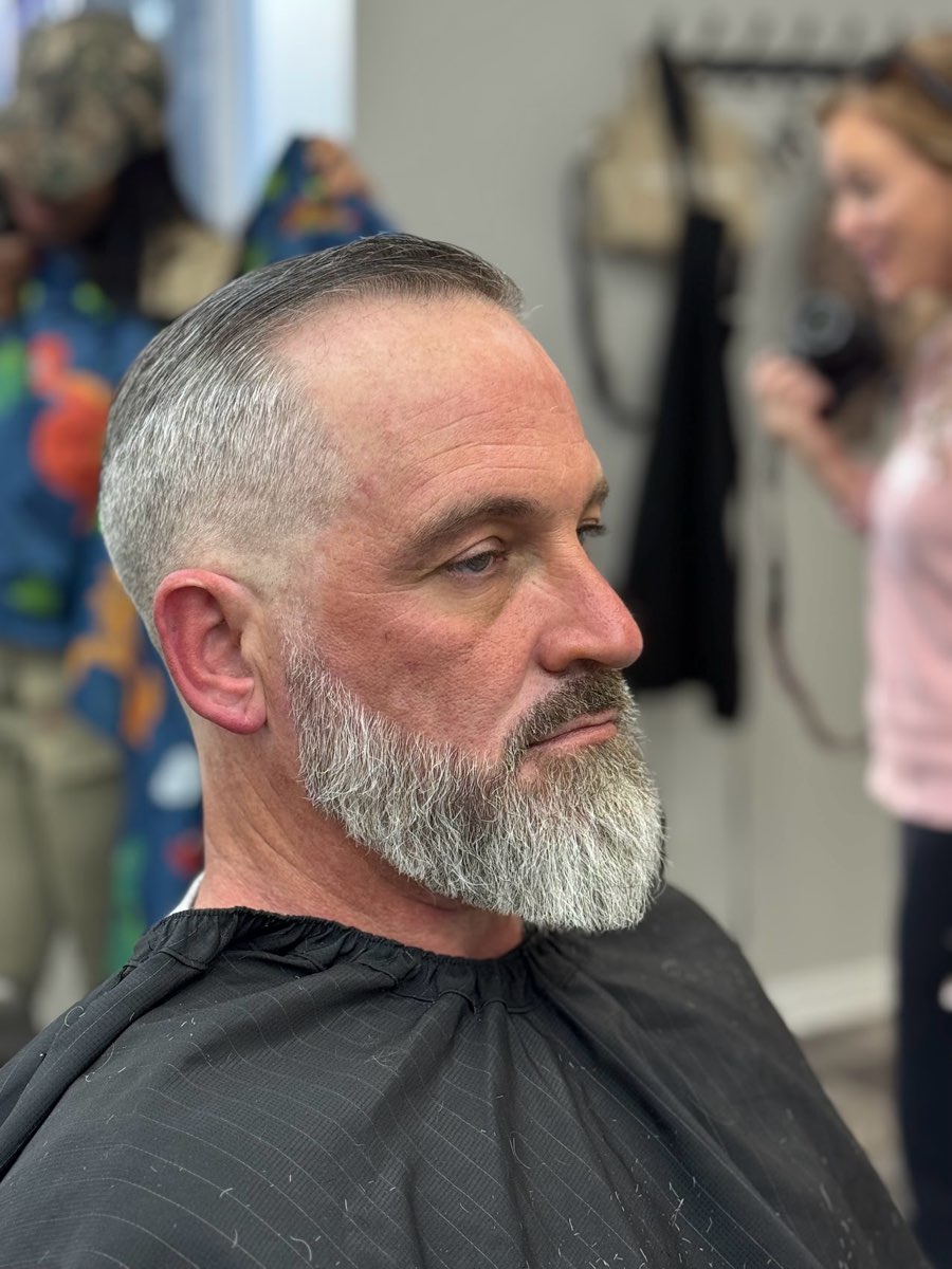 Gray hair and a full gray beard with a sharp trim