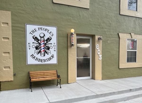 The front of The People’s Barbershop at 603 Alcovy St with its round logo sign and barber pole